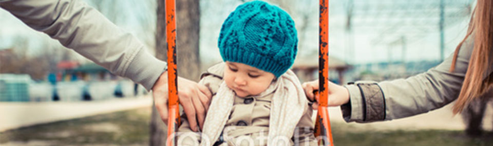 A child on the swing with two hands holding him